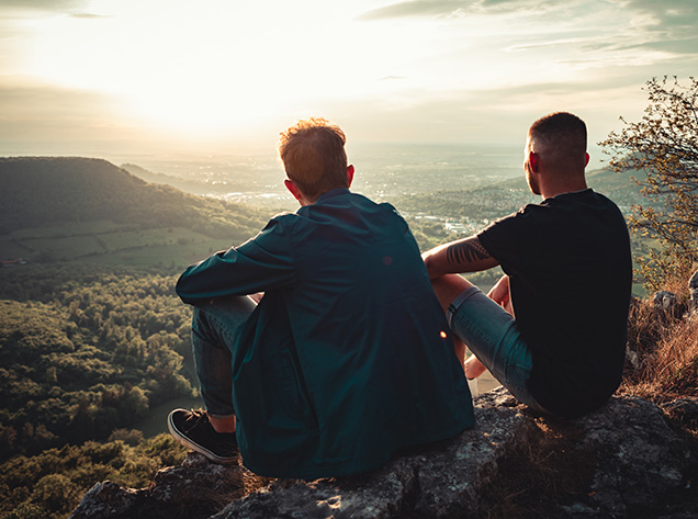 two men sitting on a hill