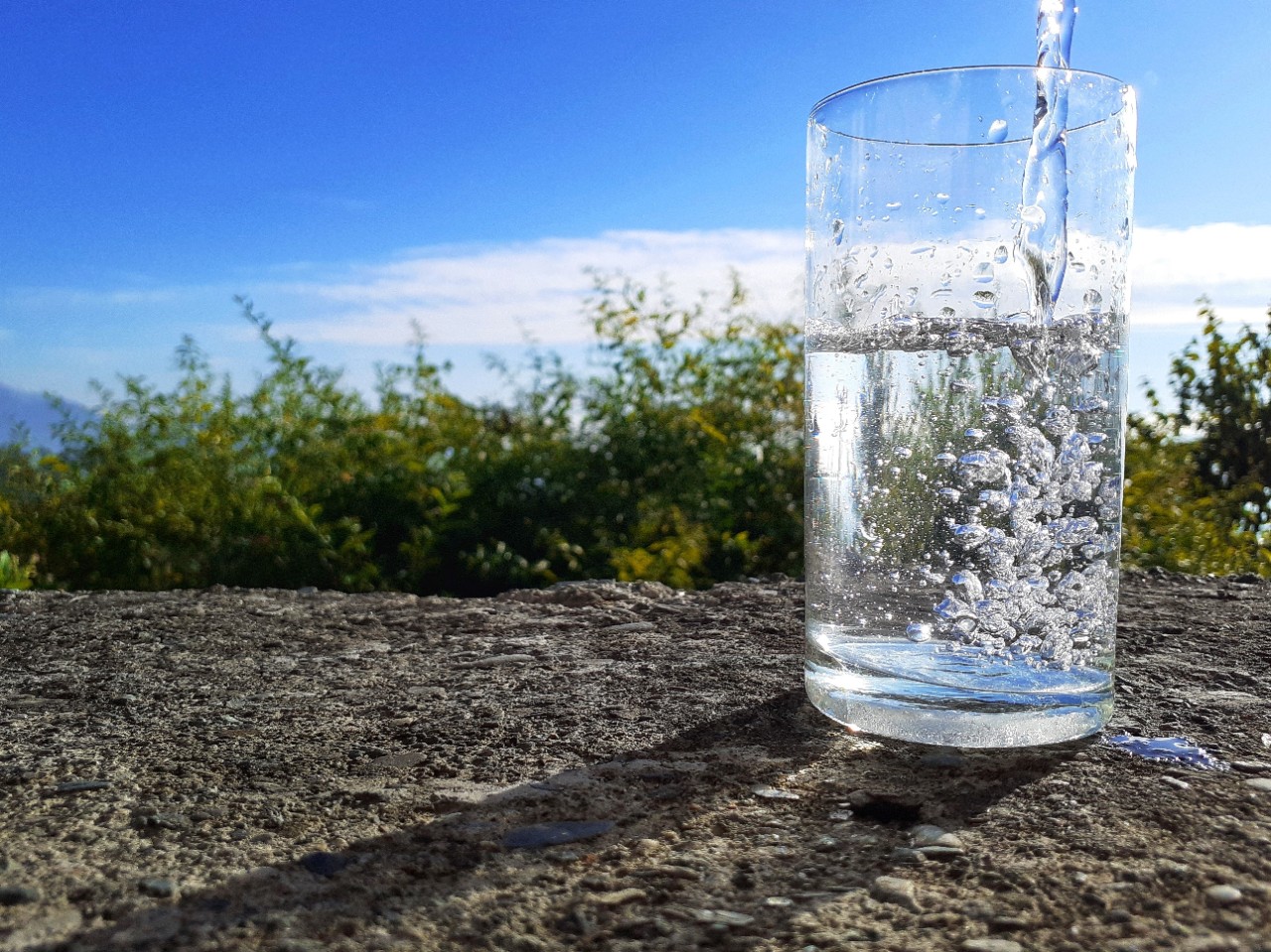 This is a picture of clean water pouring into a transparent glass taken in a natural background in a beautiful day and sunshine.