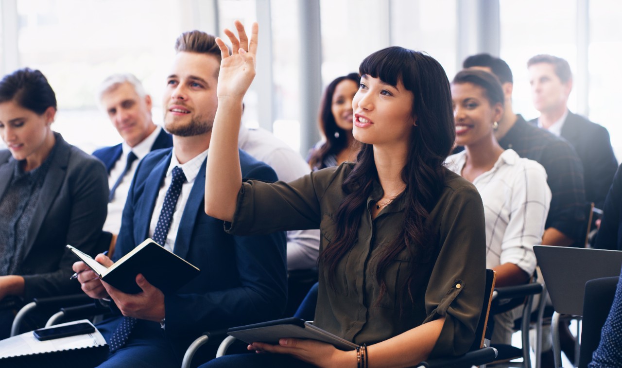 1164295069 Cropped shot of an attractive young businesswoman sitting with her diverse colleagues and raising her hand while in the office